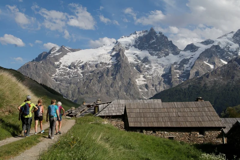 Randonneurs arrivant au hameau du Rivet de la Cime avec la Meije en toile de fond · © Cyril Coursier - Parc national des Ecrins